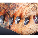 Tungsten wedding band with beveled edges and black dinosaur bone inlay